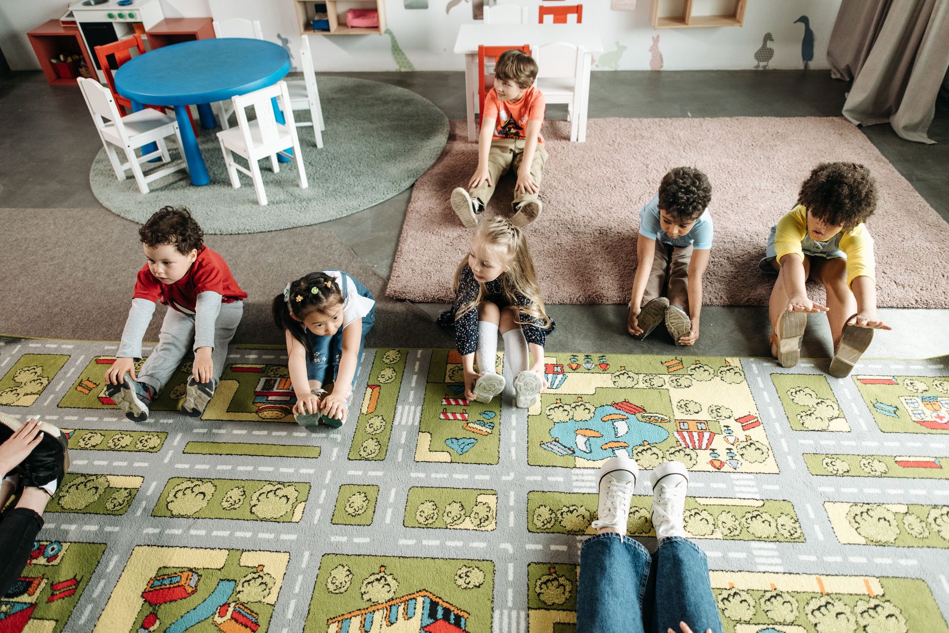 Group of diverse children performing stretching exercises in a kindergarten classroom.