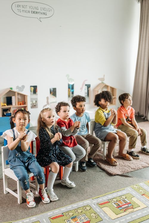 Free Children sitting together in a bright kindergarten classroom with toys and playful decor. Stock Photo
