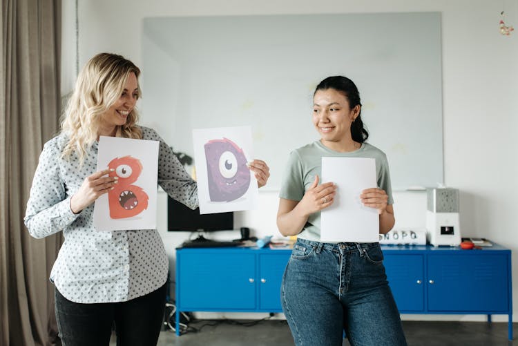 Women Holding Papers With Art Letters