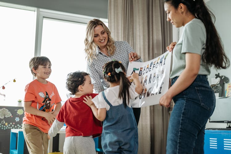 Teachers Holding A Poster Of The Alphabets