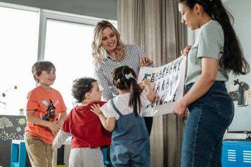 Free Preschool children and teachers enjoying an interactive alphabet learning session indoors. Stock Photo