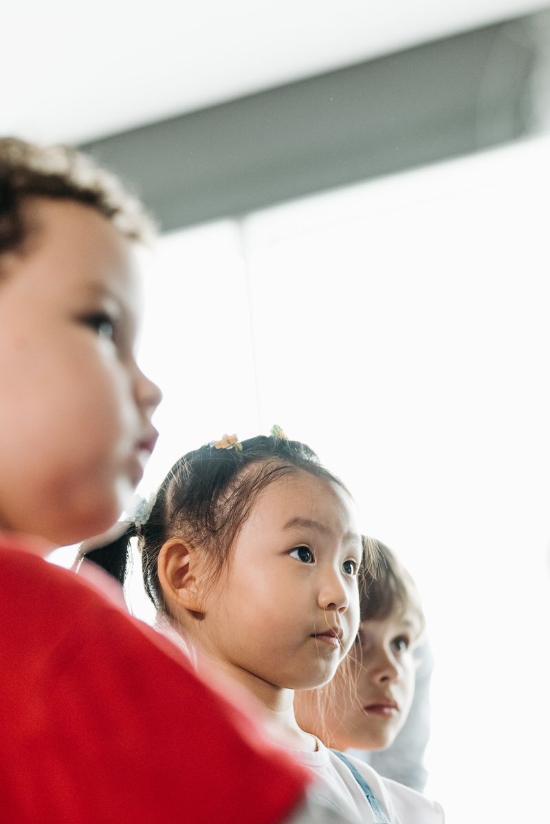 Group of young children focused indoors in natural light during nursery activity