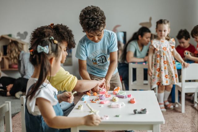 Children shaping clay together at a classroom table