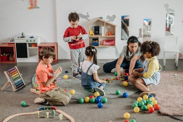 Kids With Their Teacher Playing On The Floor