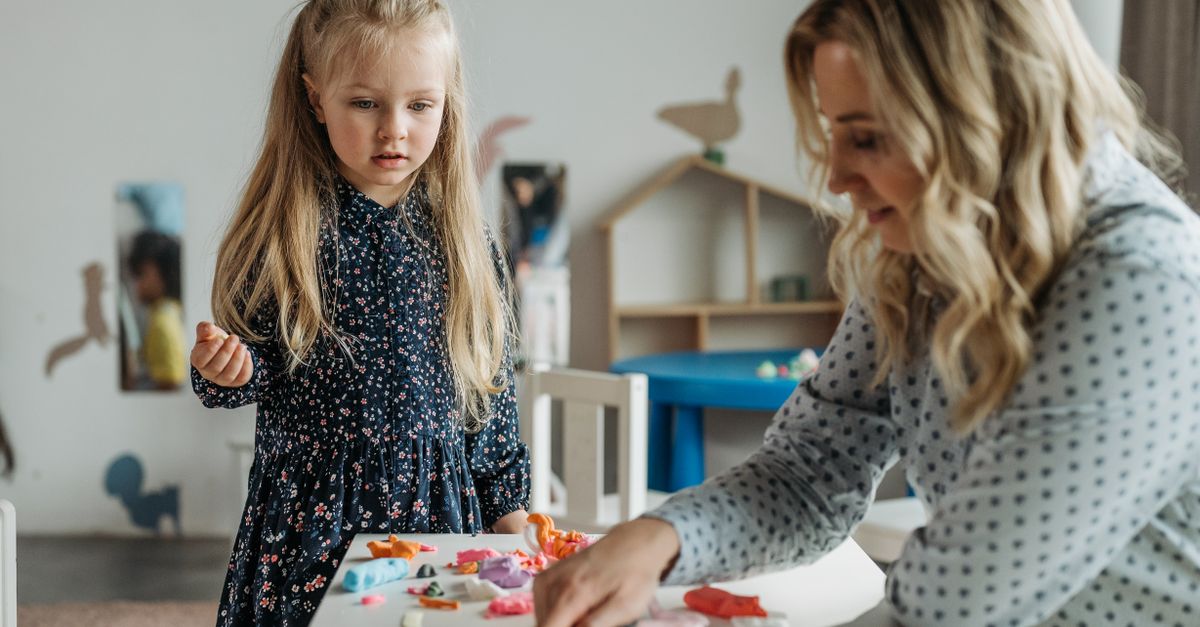 Une jeune fille et une femme participent à une activité créative dans une salle de classe de maternelle, favorisant l'apprentissage.