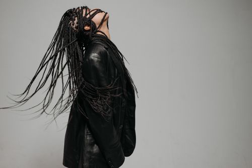 Free Stylish woman with braided hair in a black leather jacket posing in an artistic studio shot. Stock Photo