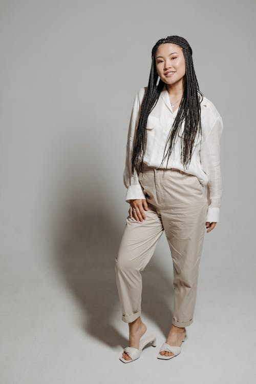 Free A Woman in White Long Sleeves Smiling while Wearing Beige Pants Stock Photo