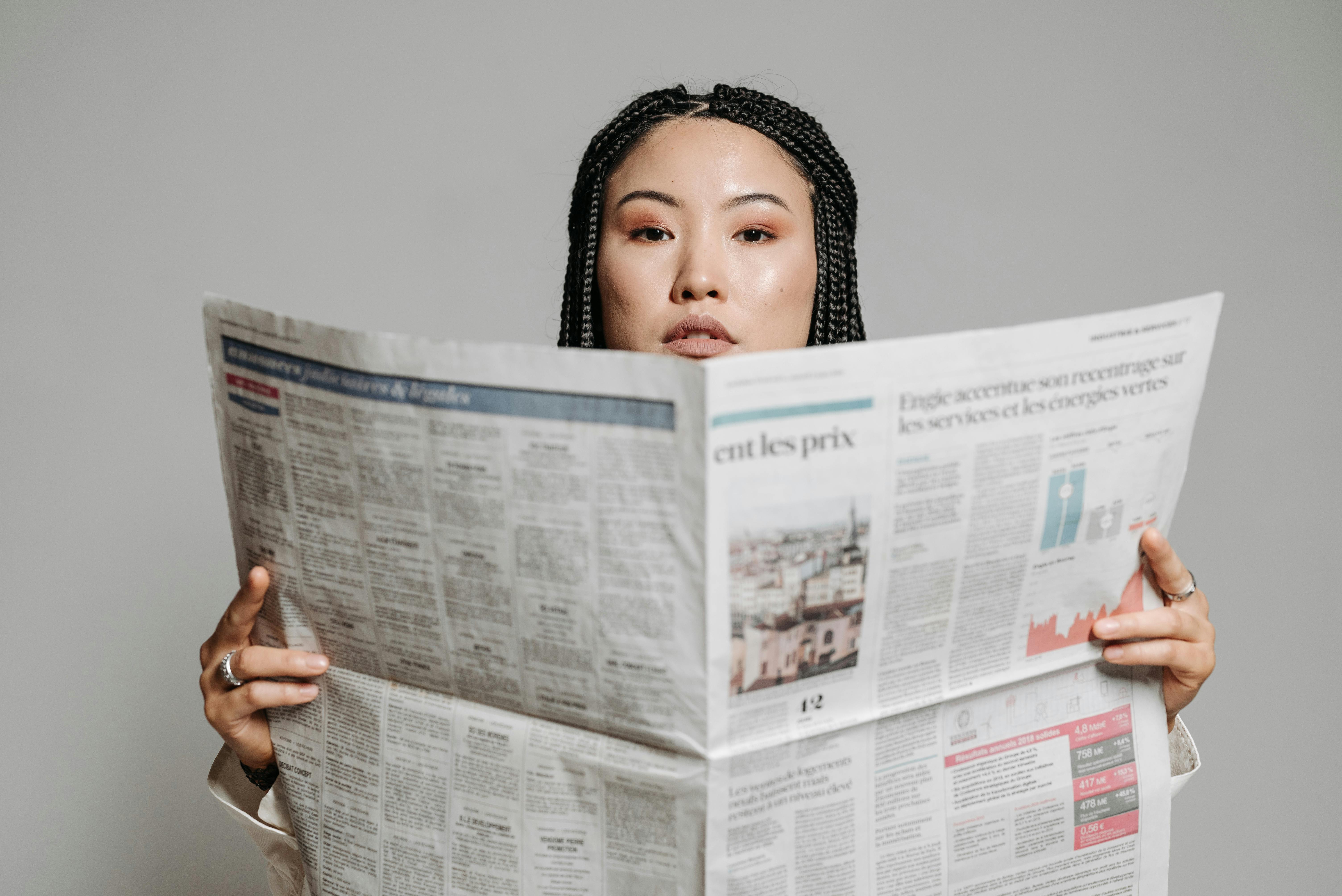 woman with braided hair holding newspaper