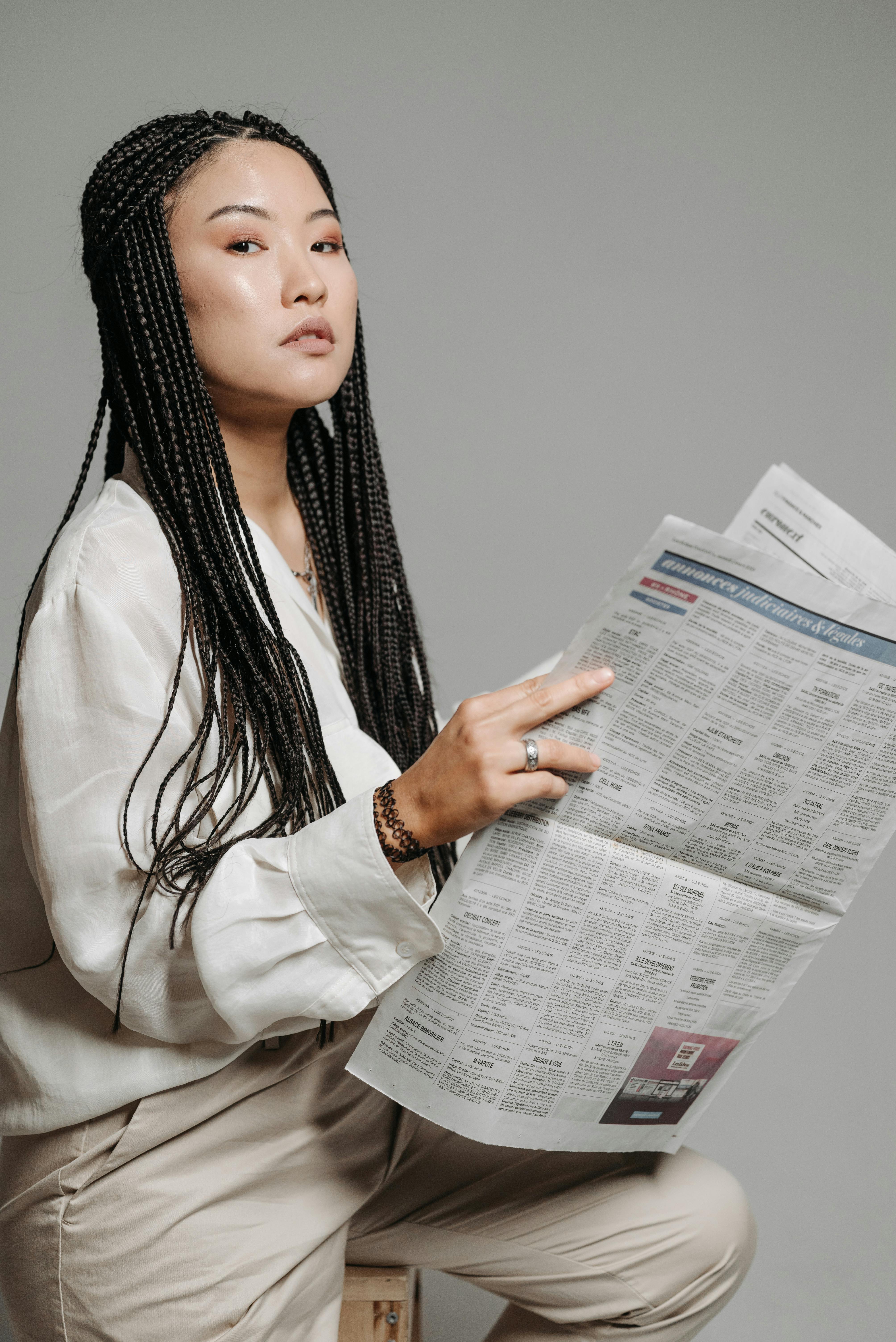 woman with braided hair holding a newspaper