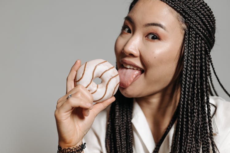 A Woman Licking A Doughnut 