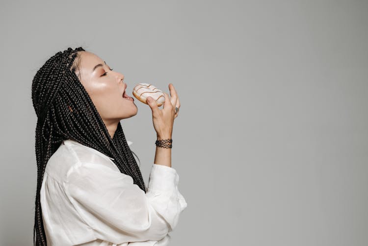 Woman With Braided Hair Eating A Doughnut 