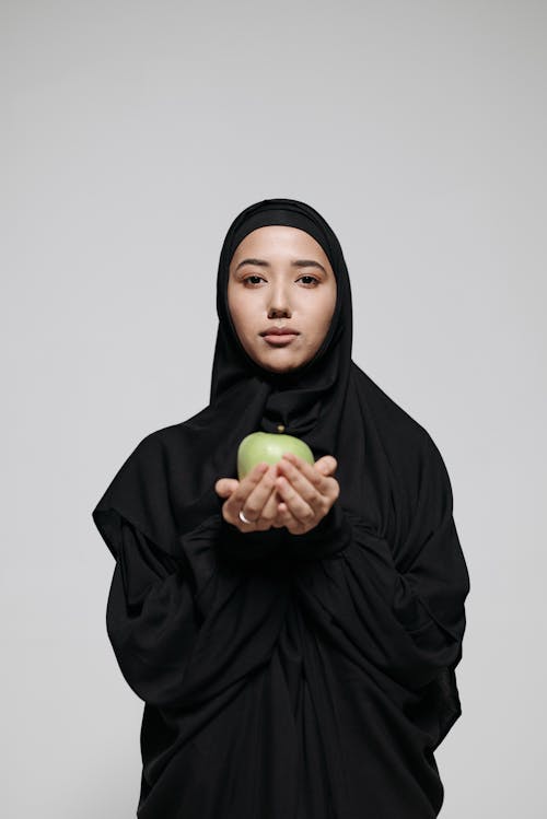 Woman in Black Hijab Holding Green Apple