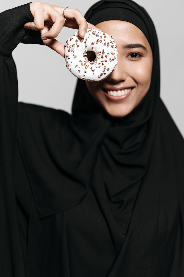 A Woman In Black Hijab Holding Donut