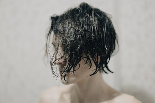 Close-up portrait of a shirtless person with wet hair and blurred background, conveying moody aesthetic.