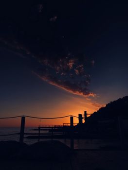 A scenic view of a beach at sunset featuring a dramatic sky over the sea.