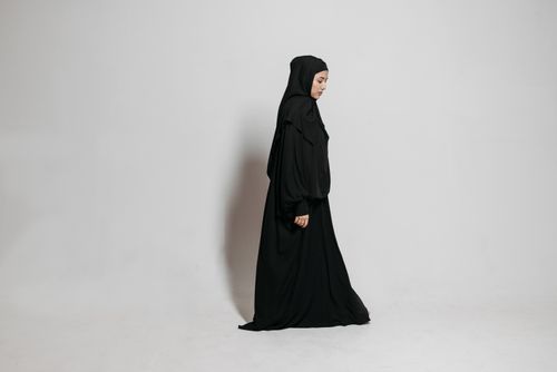 Free Studio shot of a woman in traditional black abaya and hijab, eyes closed, side view. Stock Photo