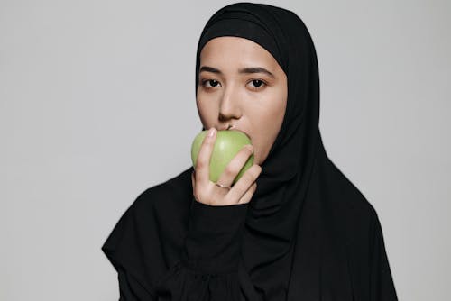 Woman in Black Hijab Holding Green Apple