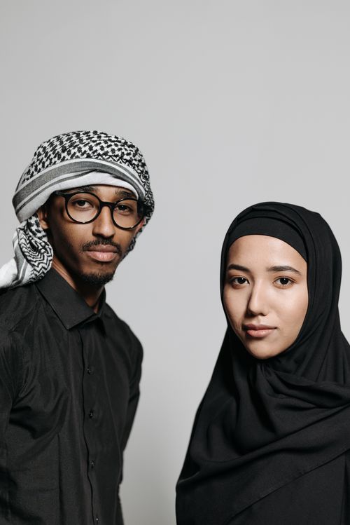 Free A captivating studio portrait of a Muslim man and woman posing with elegance on a white background. Stock Photo