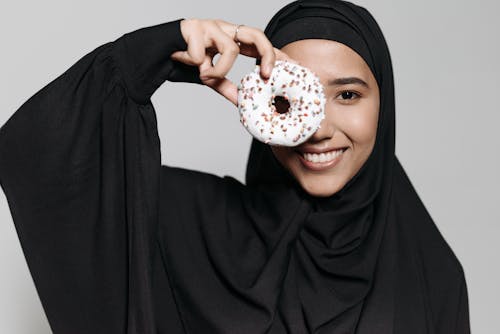 Woman in Black Hijab Holding Donut