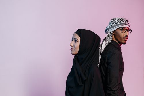 Free Portrait of a Muslim couple in traditional attire against a pink backdrop, showcasing cultural fashion. Stock Photo