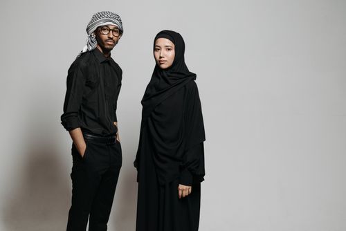 Free Elegant portrait of a man and woman in traditional Middle Eastern attire on a neutral background. Stock Photo