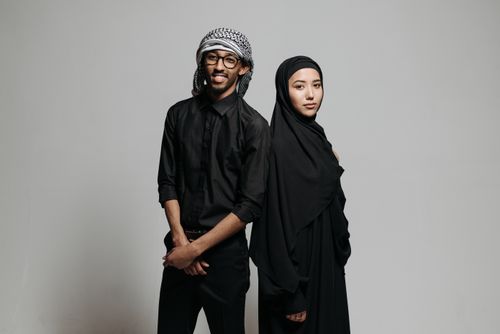 Free Studio portrait of a Muslim couple dressed in traditional clothing, standing against a white backdrop. Stock Photo