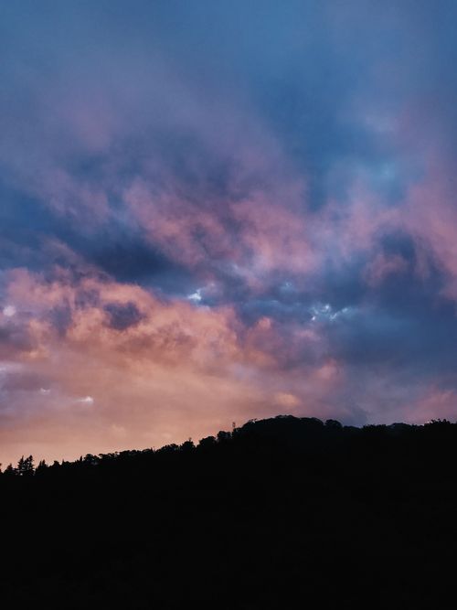 Free A mesmerizing view of a dramatic sky during sunset with a landscape silhouette. Stock Photo