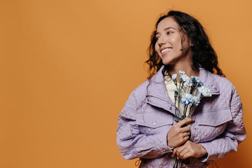 Woman in Purple Jacket Holding Flowers