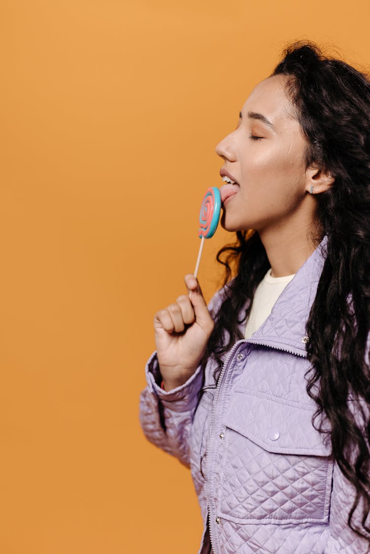 Woman In Purple Jacket Licking A Lollipop