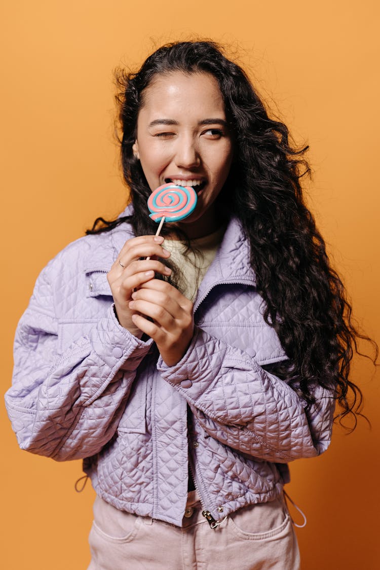 Woman In Purple Jacket Biting A Lollipop