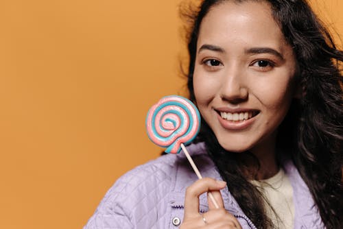 A Smiling Woman Holding a Lollipop