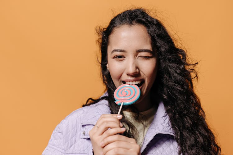 Woman In Purple Jacket Biting A Lollipop