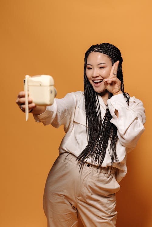 Asyalı kadın, Barış işareti, dikey atış içeren Ücretsiz stok fotoğraf
