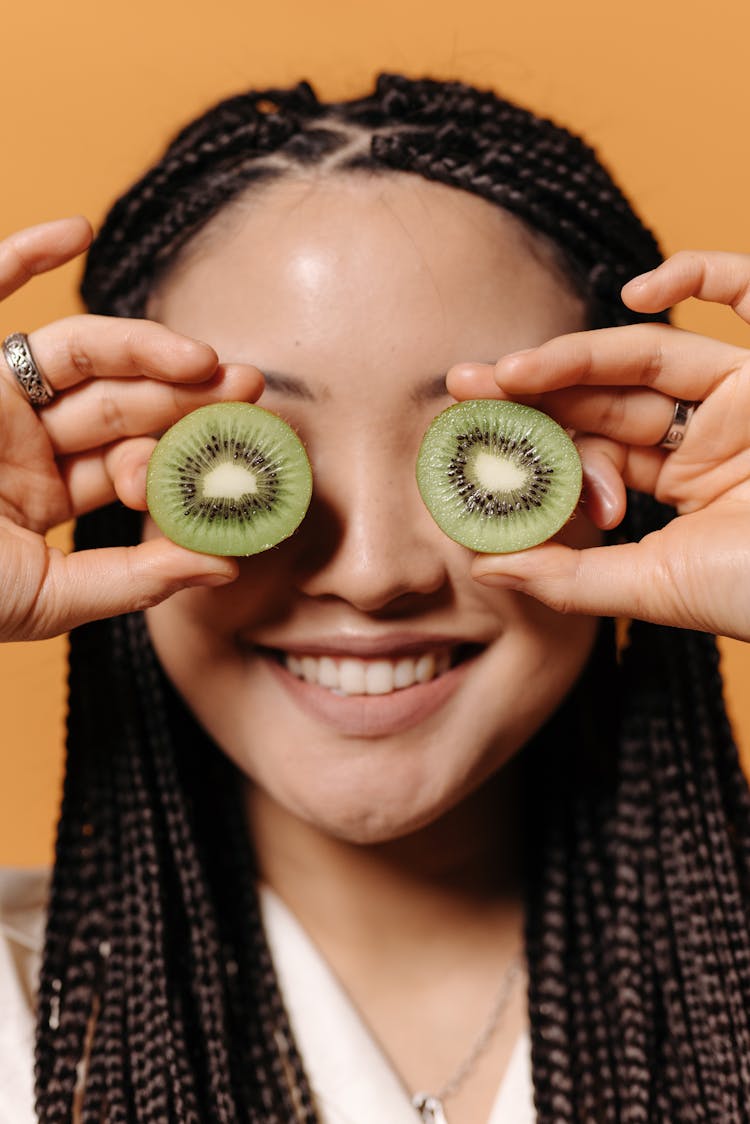 A Woman With Slice Kiwi Fruit Over Her Eyes