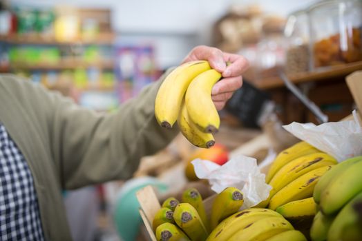 A hand holding fresh bananas in a vibrant Portuguese market. Ideal for food and lifestyle themes.