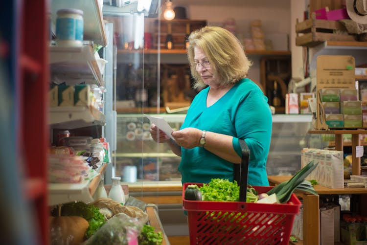 Woman In Green Shirt Looking At Her Grocery List