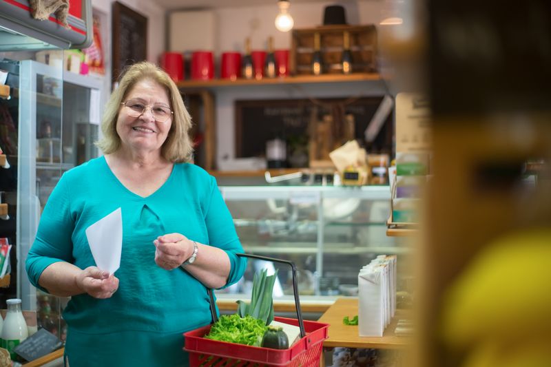 A smiling woman holding a basket in a Portuguese grocery store, enjoying her shopping experience.