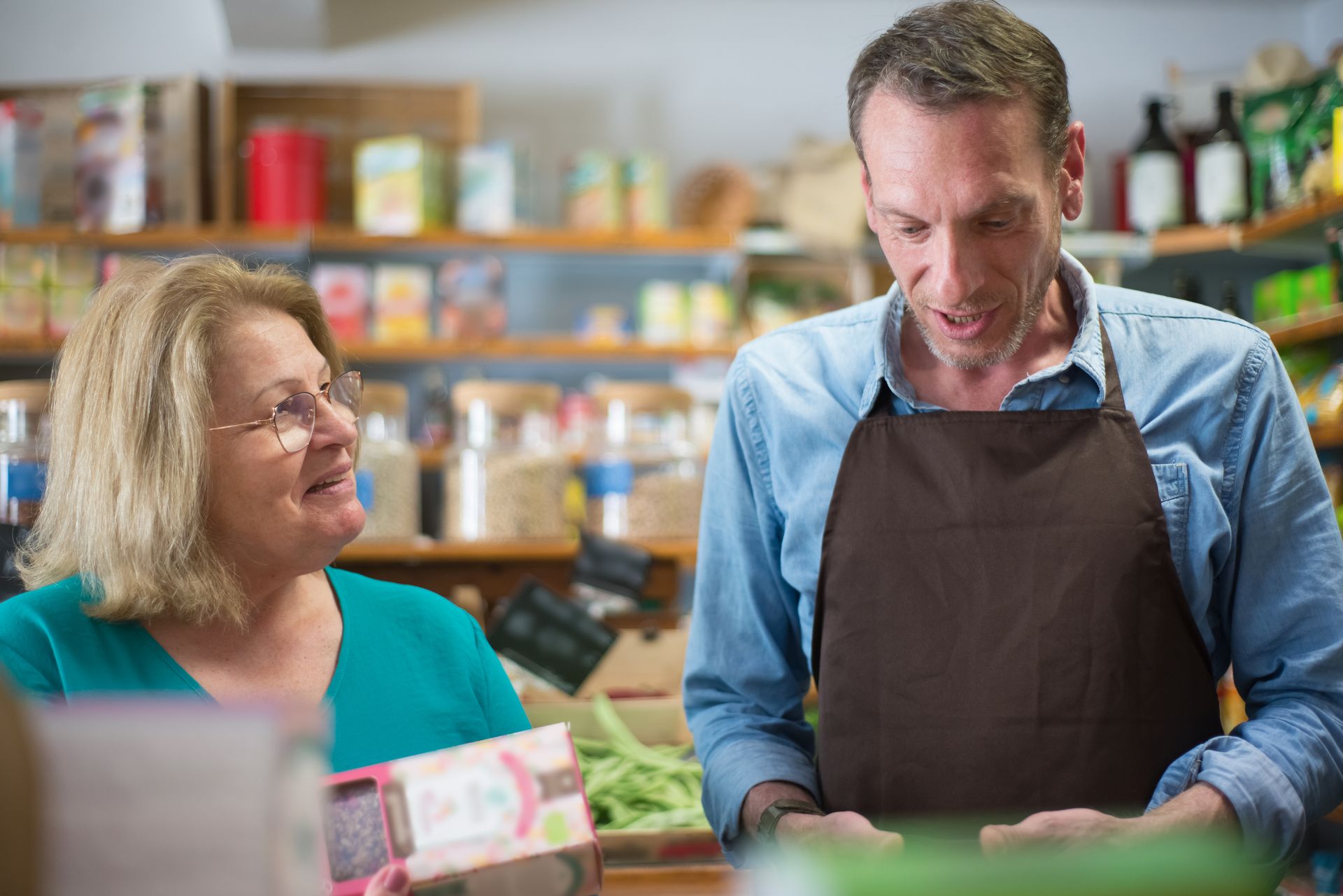 A woman customer and a male store clerk engaged in conversation in a Portuguese grocery store.