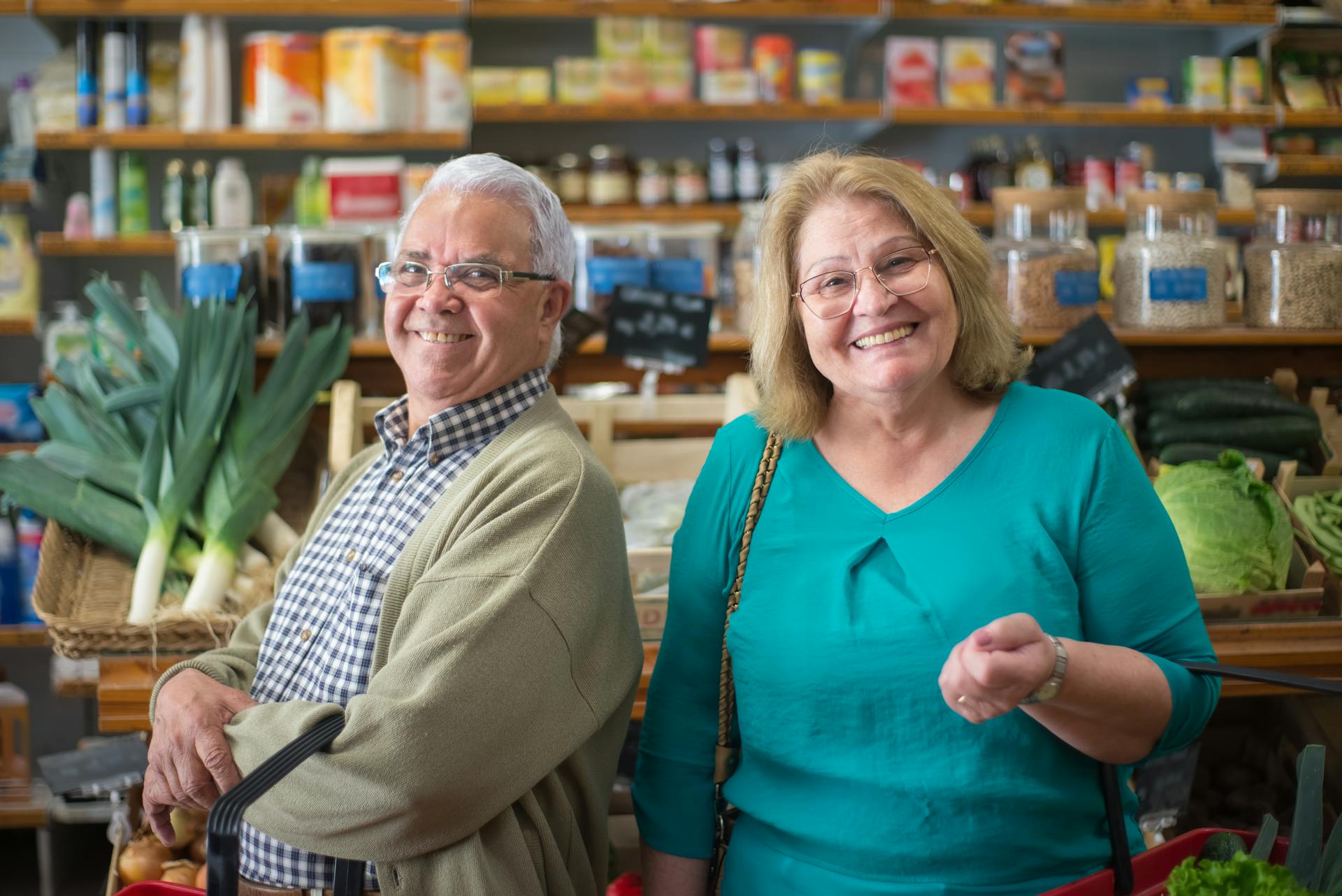 Cheerful senior couple shopping for fresh vegetables in a Portuguese grocery store.