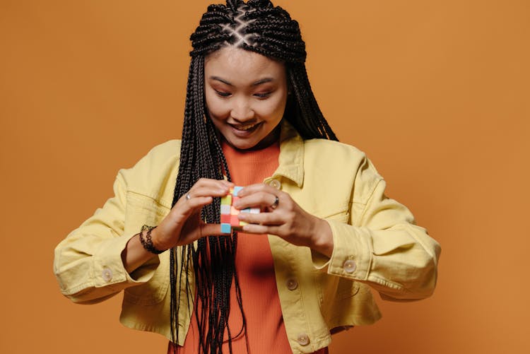 Smiling Woman In Yellow Jacket Solving A Rubik's Cube