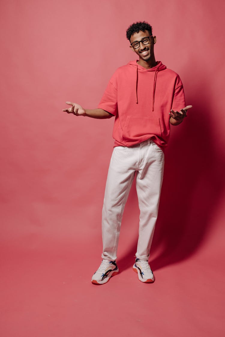 Confident Man In Pink Hoodie And White Pants Smiling