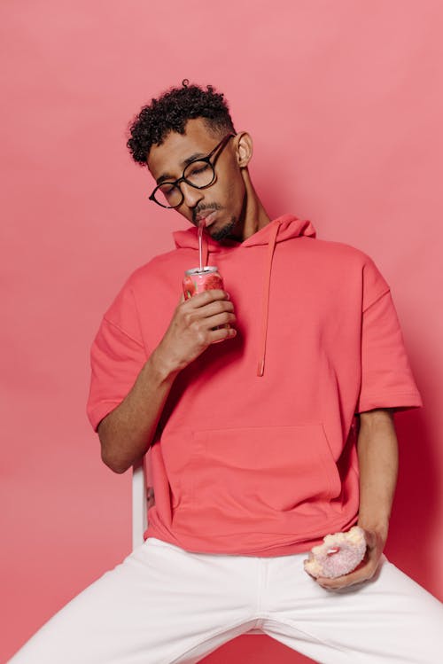 Woman in Pink Hoodie Drinking from a Straw