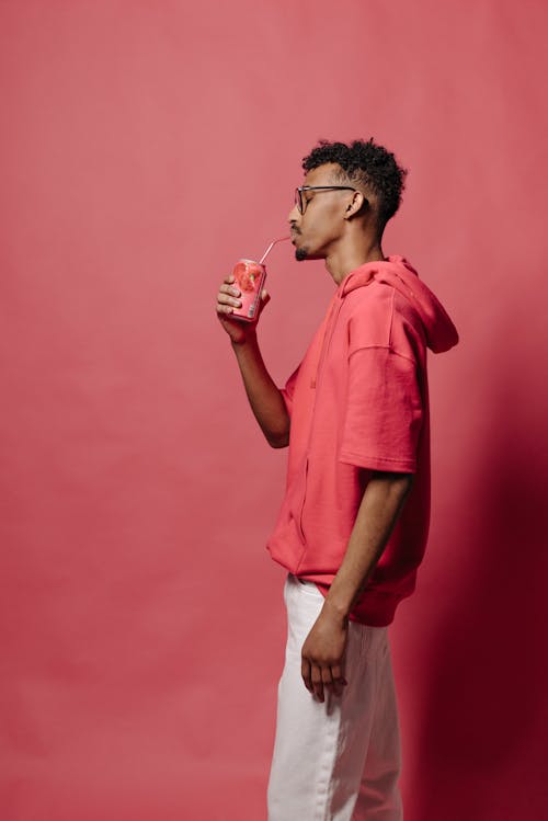 Side View of Man in Pink Shirt drinking from a Can 