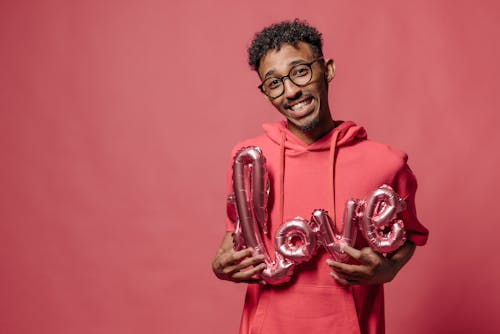 Man in Pink Shirt Hoodie holding a Balloon 