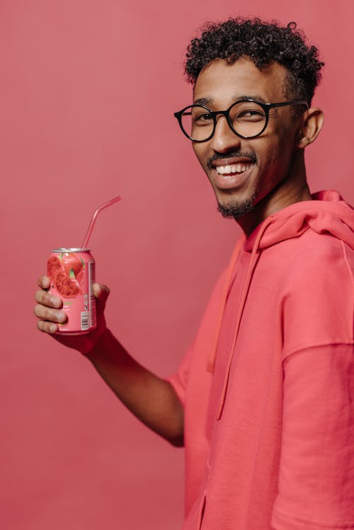 Man in Pink Hoodie Holding Strawberry Drink in Can