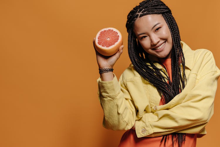 Woman Smiling While Holding A Sliced Fruit