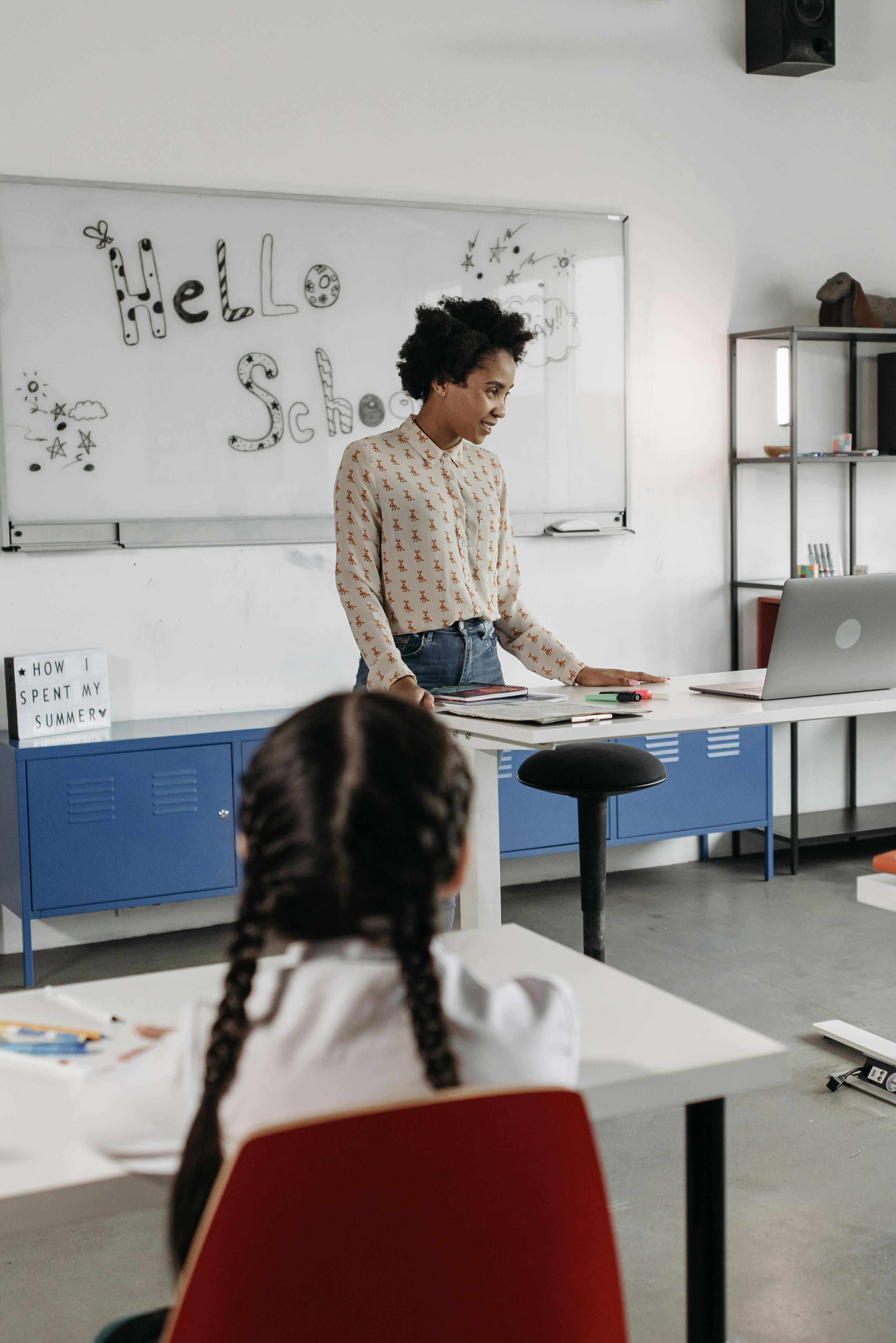 elementary school teacher behind the desk in the classroom on the first day of the new school year