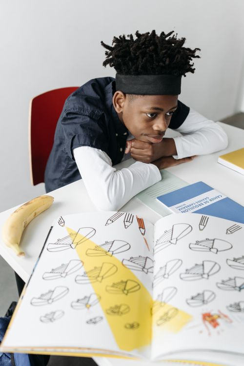 Free A young boy attentively studies in a classroom with open books on the desk. Stock Photo