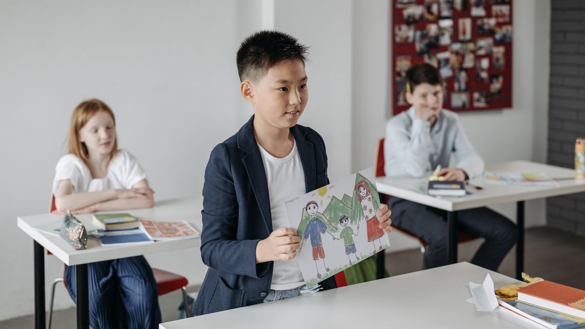 Child showcasing drawing in a classroom setting, focusing on education.