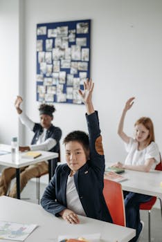 Children in a modern classroom raise hands during an engaging lesson.